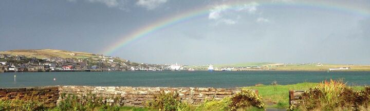  Looking over stone wall to sea with rainbow in sky