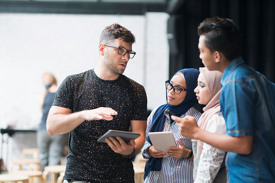 Group of young people with handheld tablets in discussion