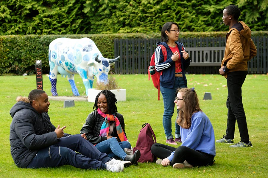 Group of students on the grass opposite the main entrance, London Campus